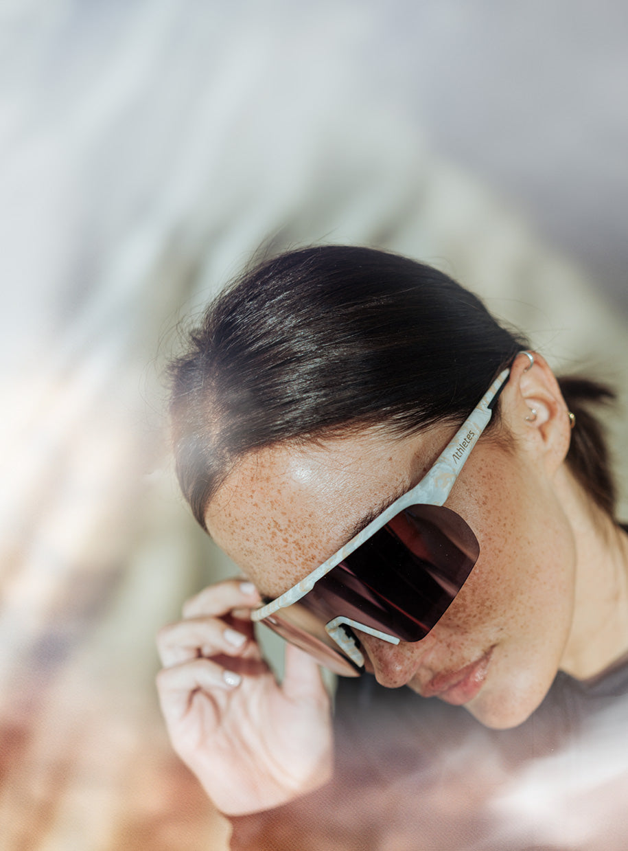 Mujer con gafas de sol deportivas con cristales oscuros y montura clara, primer plano