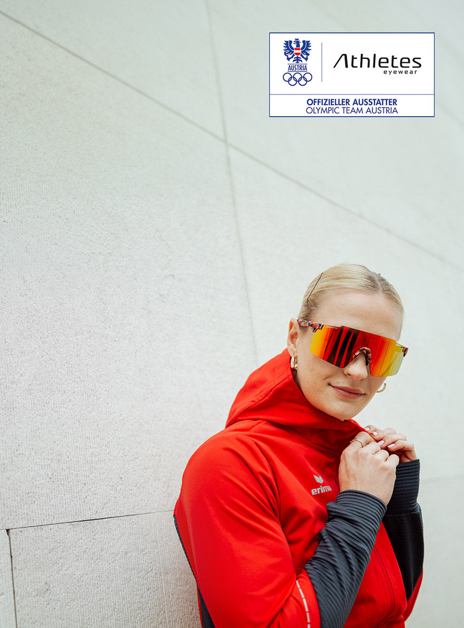 Mujer del equipo olímpico austriaco con chaqueta deportiva roja y gafas de sol deportivas