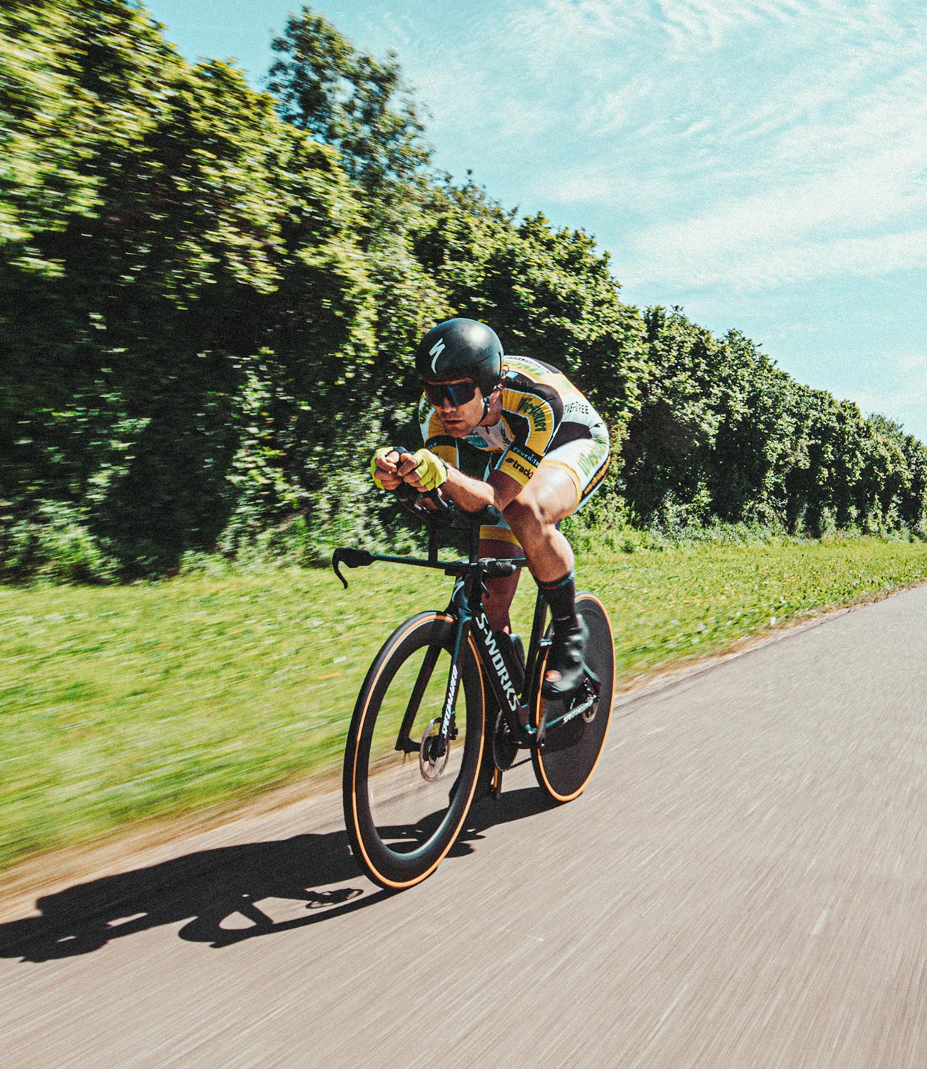 Ciclista de carretera circulando por una carretera, equipado con casco y gafas de sol de ciclista; Christoph Strasser © Lex Karelly